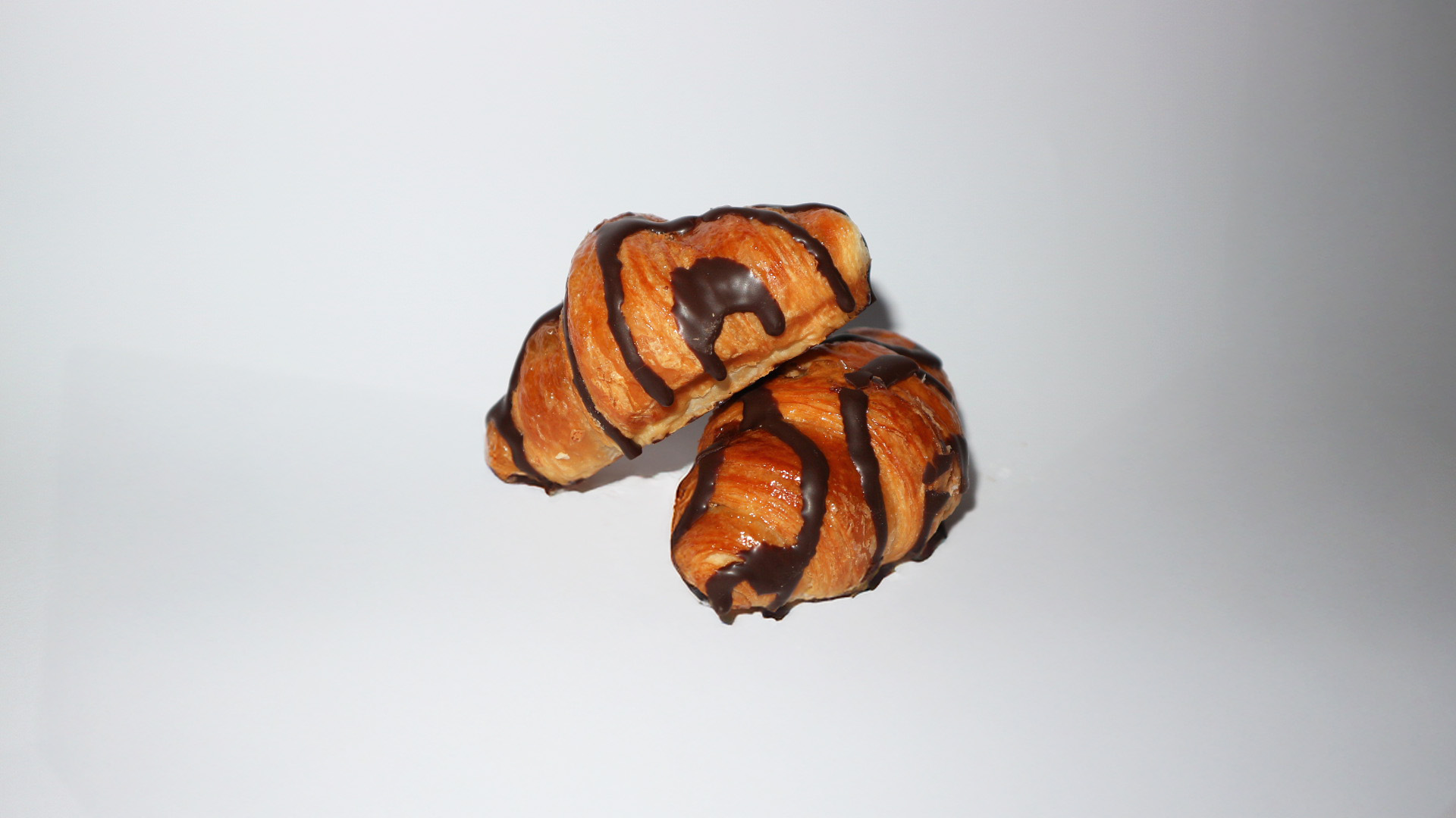 Croissant decorado de chocolate Belcan, hojaldre crujiente con acabado vistoso